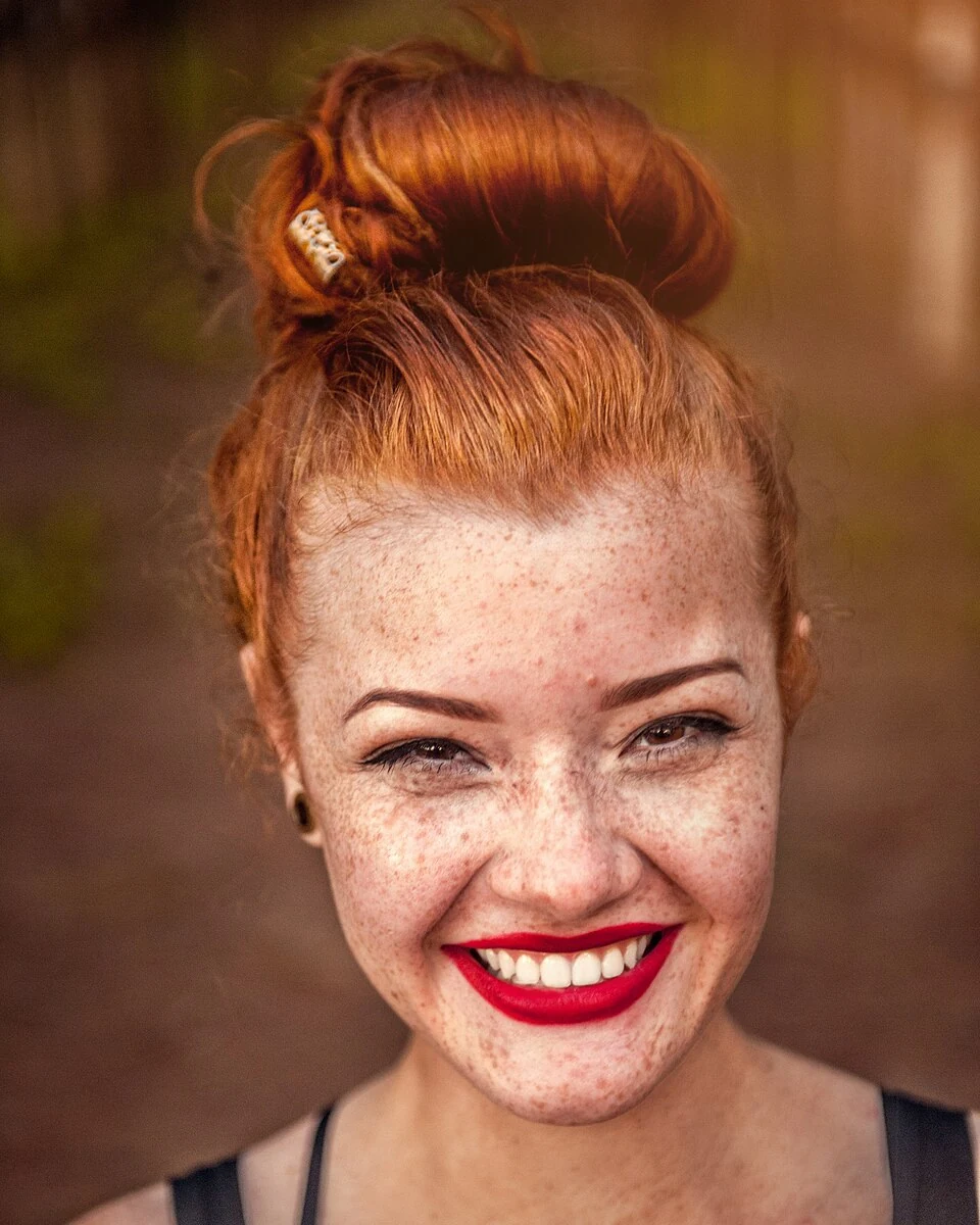 Paciente sorrindo, de batom vermelho, depois do tratamento